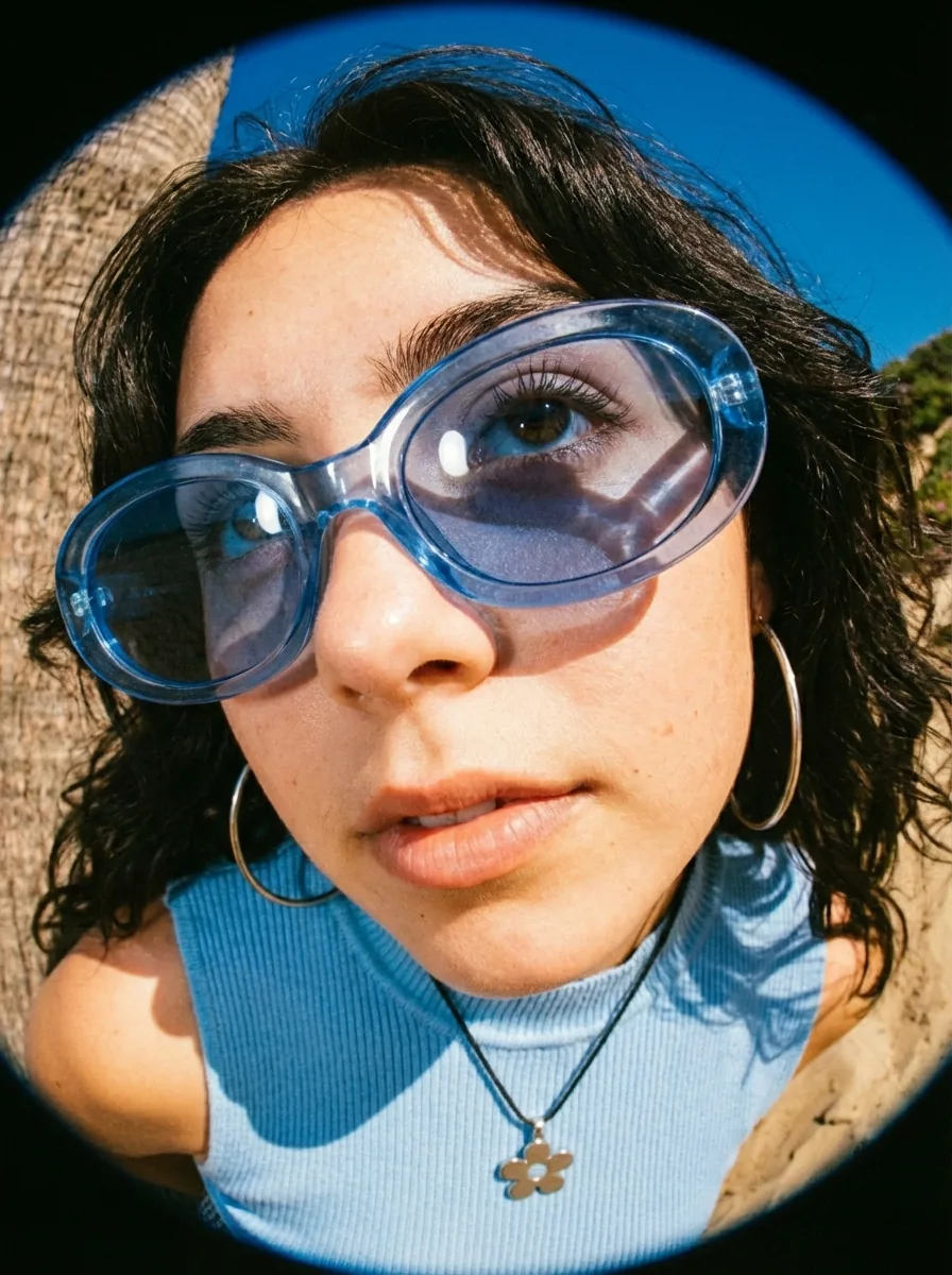 Fisheye lens portrait of a woman wearing blue-tinted sunglasses